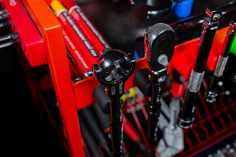 A ratchet and extensions being mounted on magnetic button tool organizers